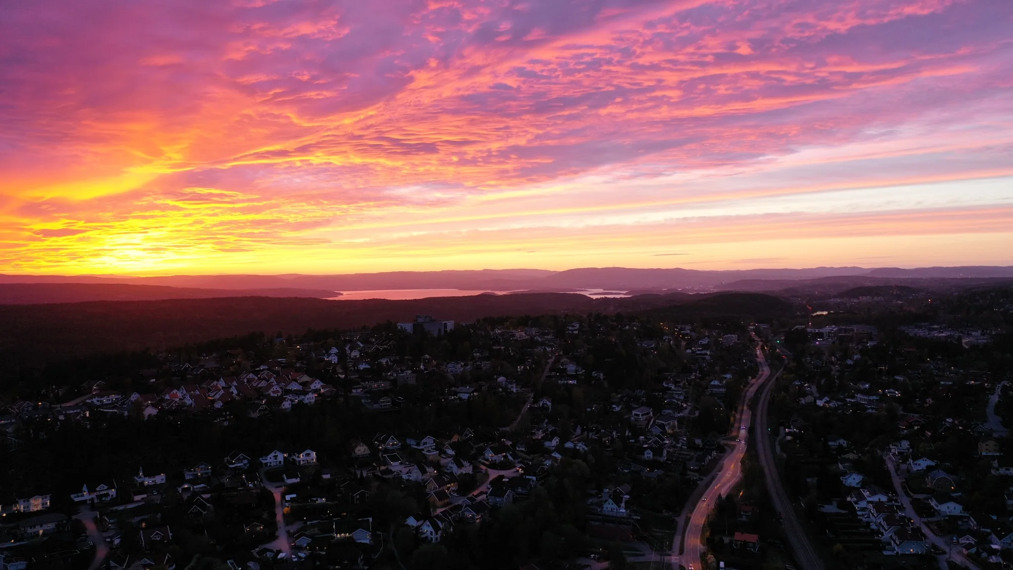 Solnedgang over bebyggelse sett fra drone